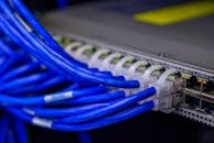 Introduction To Cisco Switches: Switching made simple!! Detailed view of blue ethernet cables connected to a network switch in a data center.